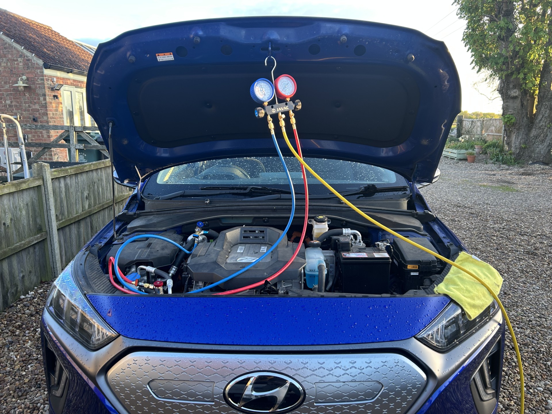 Air conditioning manifold gauges connected to an electric vehicle's engine bay during a re-gas